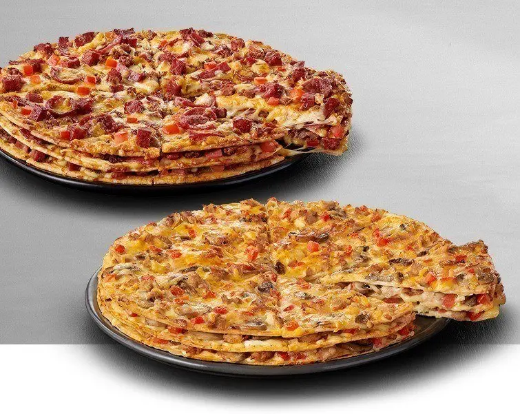 Two large triple decker pizzas on a wooden table
